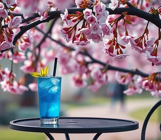 Image shows an overhanging branch with beautiful budding blossoms, and the top of a bistro table with bright blue cocktail in a glass on it.