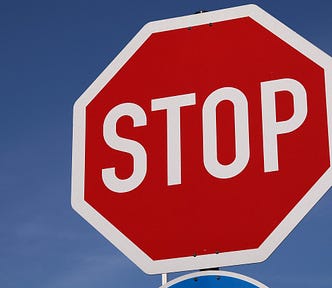Image shows a huge stop sign filling the right of the image with a blue sky background.