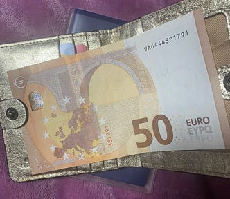 A golden wallet with €50 note on top.