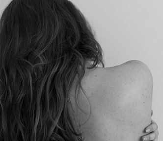 The back of a bare shoulder and head with long hair