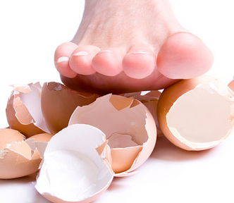 Foot about to step on cracked eggshells.