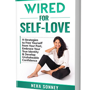 This is the cover of a #1 bestselling book titled Wired For Self-Love. The Text in large font in teal ink reads “Wired For Self-Love”. The smaller font text below it in black ink reads “11 Strategies to Free Yourself from Your Past, Embrace Your True Identity & Develop Unshakeable Confidence. A lady with a big smile sits in a casual pose with her jet black hair falling on her left shoulder. She’s wearing a white blouse, black pants and bracelet. Her smile oozes confidence. She’s the author.