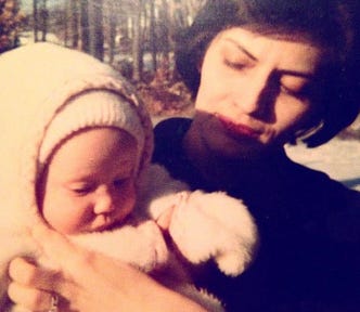 My mom is holding me as a baby; I have on a fleece onsie. Judging by the age and the backdrop of denuded trees, I think we’re in Waltham, Mass.