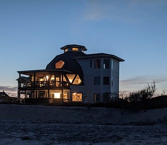 Night shot of a domed house with lights glowing through all the windows.