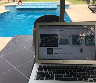 A laptop sits on a table with a pool in the background.