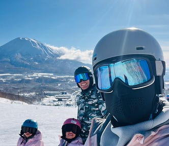 Picture of a family of 4 skiing with a mountain in the background