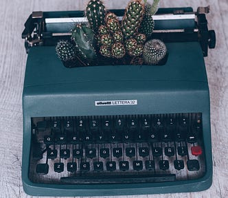 A typewriter with cacti growing out of it.
