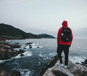 7 Powerful Life Lessons From Living Out of 2 Backpacks For Years — man with red jacket standing on lake