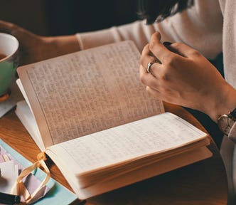 Photo of a person holding a cup and reading a diary.