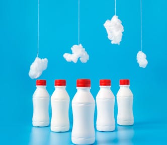 white bottles with red caps lined up against a blue background with white cotton batting dangling above