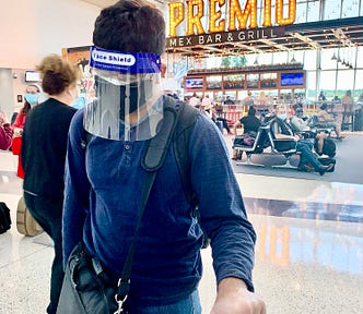 Passenger waiting in airport wearing two masks and a face shield