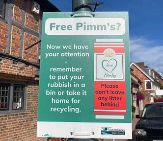 A street sign in Henley in South Oxfordshire, England. It’s on a green rectangular background. It says “Free Pimm’s? Now we have your attention. Remember to put your rubbish in a bin or take it home for recycling.” There is a motif of a red Pimm’s can which says “Love Henley. Please don’t leave any litter behind.”