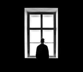 A man standing near a window, a moment of realization and reflection.