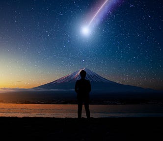 Imagem de um céu azul e alaranjado ao anoitecer, já estrelado com um cometa passando e a silhueta de uma pessoa de costas, com uma montanha ao fundo