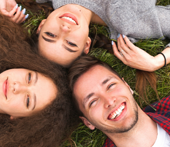 Three people laying in the grass — This Phrase Convinced Women To Have a Threesome 86% of the Time