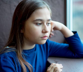 Little girl sad and alone staring out of window