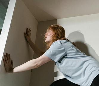 anxious woman pressing hands against wall