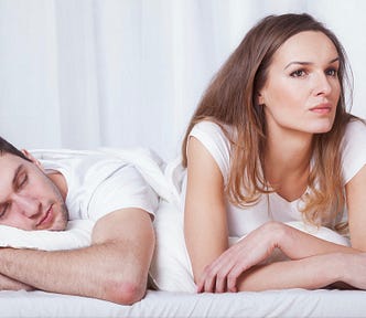 couple in bed man sleeping pensive woman