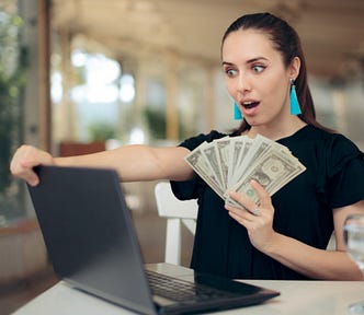 Woman with cash in front of laptop