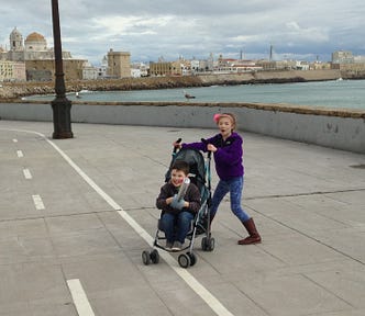 A young girl pushes her 5-year-old brother in a stroller in the waterfront area of Cadiz, Spain.