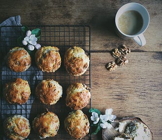 A number of date and walnut scones fresh from the oven with a cup of coffee.