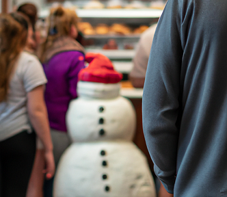 A snowman standing in line in a bakery