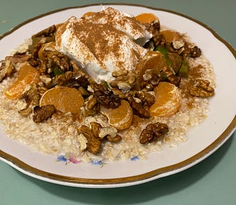 A bowl of oats covered in oranges, walnuts, kiwis, yogurt and cinnamon