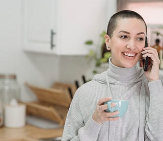 Happy woman speaking on smartphone with cup of tea