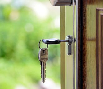 An open entry door with a key inserted in the lock.