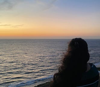 Divya overlooking sunset on the ocean, contemplating self-worth and online validation. Escaping the cycle of self-doubt and comparison in the digital age.