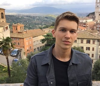 ryan shannon boy man posing in perugia italy scenic italian background, orange warm colored building, greenery and trees italian countryside