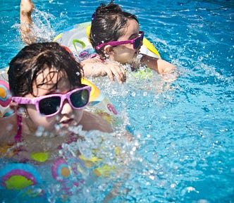 Two children floating in water, inside colorful floats.