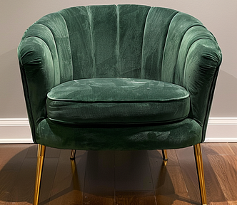 A fontal shot of a green velvet accent chair with gold legs