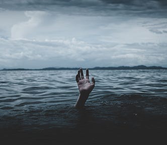 Ocean with hand reaching out of water towards dark clouds