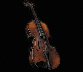 An old, but playable, used violin on a black background.