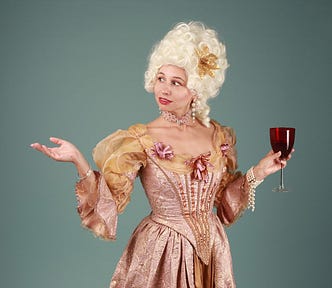 Image of a woman wearing a white wig reminding us of the royalty in the middle ages, and a glamorous old dress holding a wine of glass in her left hand, and her right hand up in the air, as if motioning while talking. She looks in the direction of her right hand.