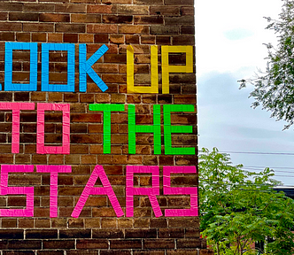 Brick wall with the words “Look up to the starts” written on it.