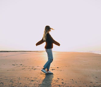 Girl spinning around on an empty beach