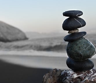 Grey pebbles stacked on top of each other with grey toned beach scene behind