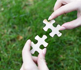 Image of a person trying to put together two pieces of a jigsaw puzzle.