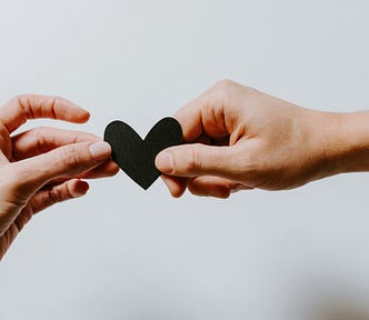 Two people holding a heart between their hands