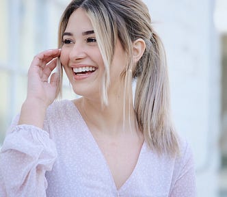 happy girl with hair in ponytail wearing white top