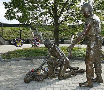 a bronze statue of a nurse and a soldier leaning over a wounded soldier on the ground — Vietnam veterans benefits