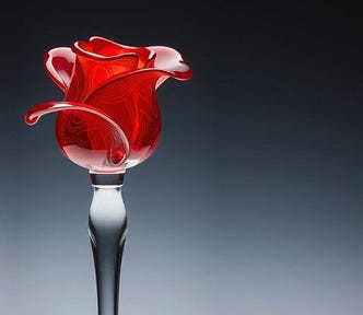 Image shows a red rosebud of glass on a clear glass stem against a grey-black background.