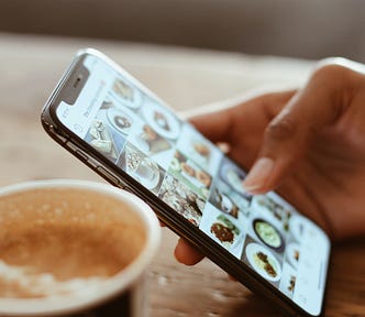 Mobile phone showing instagram feed and a cup of coffee