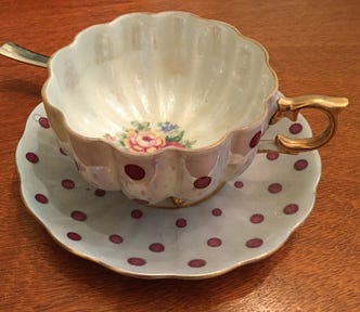 A vintage cup and saucer with gilt edges and a red polka dot pattern.