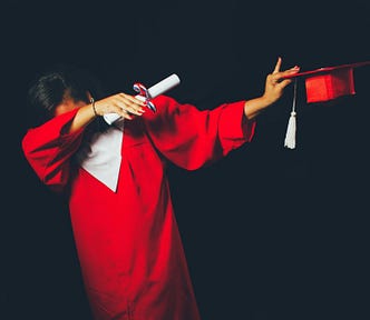 Photo of women wearing red graduation gown, doing the popular dance dapping while holding a graduation hat and rolled diploma.