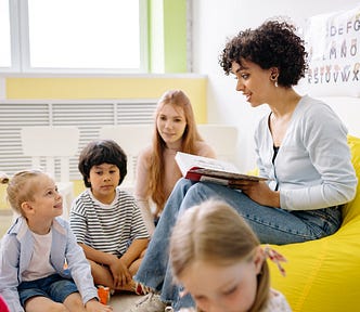 A woman reading a book to children at a kindergarten