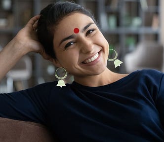 Happy, smiling young woman wearing a blue top sitting on couch, relaxed