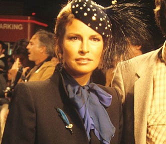 Raquel Welch wearing a hat and a pussy bow blouse.